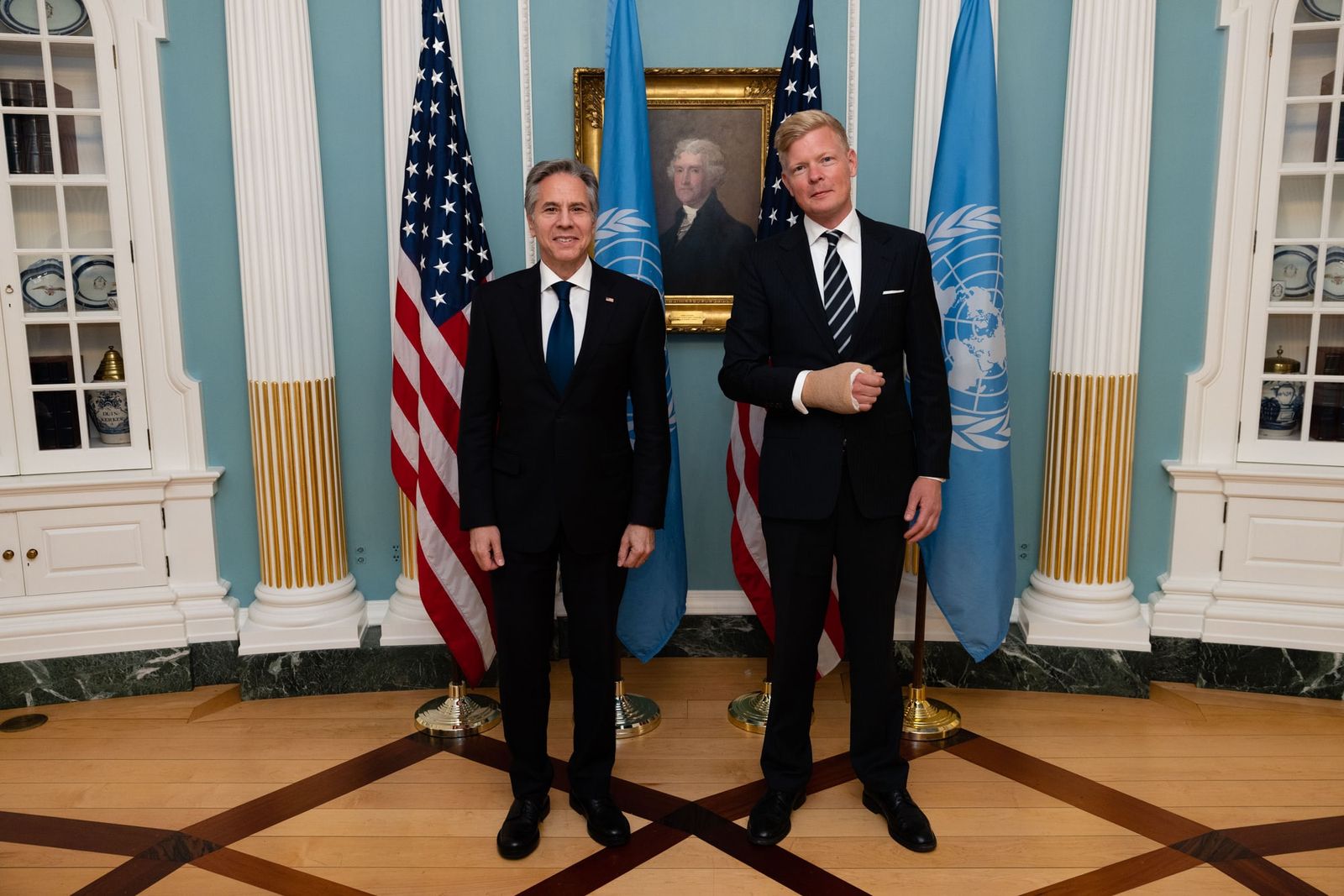 Hans Grundberg and Antony Blinken stand side by side in a State Department room, in front of US and UN flags.