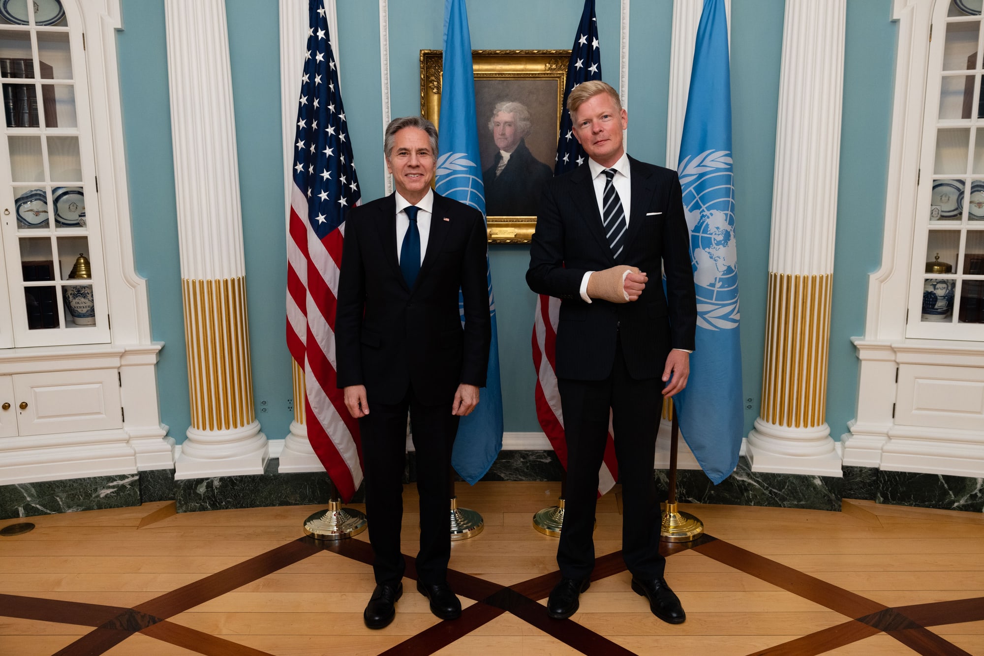 Hans Grundberg and Antony Blinken stand side by side in a State Department room, in front of US and UN flags.