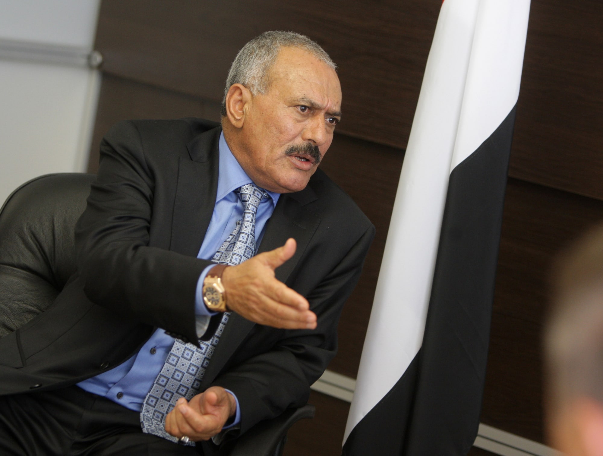 Ali Abdullah Saleh in a dark suit, gesturing as he speaks in a meeting.