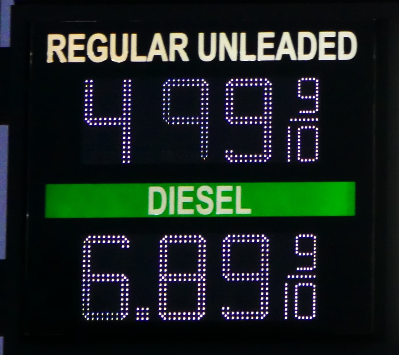 A petrol station price board showing regular unleaded at $4.99 and diesel at $6.89 a gallon