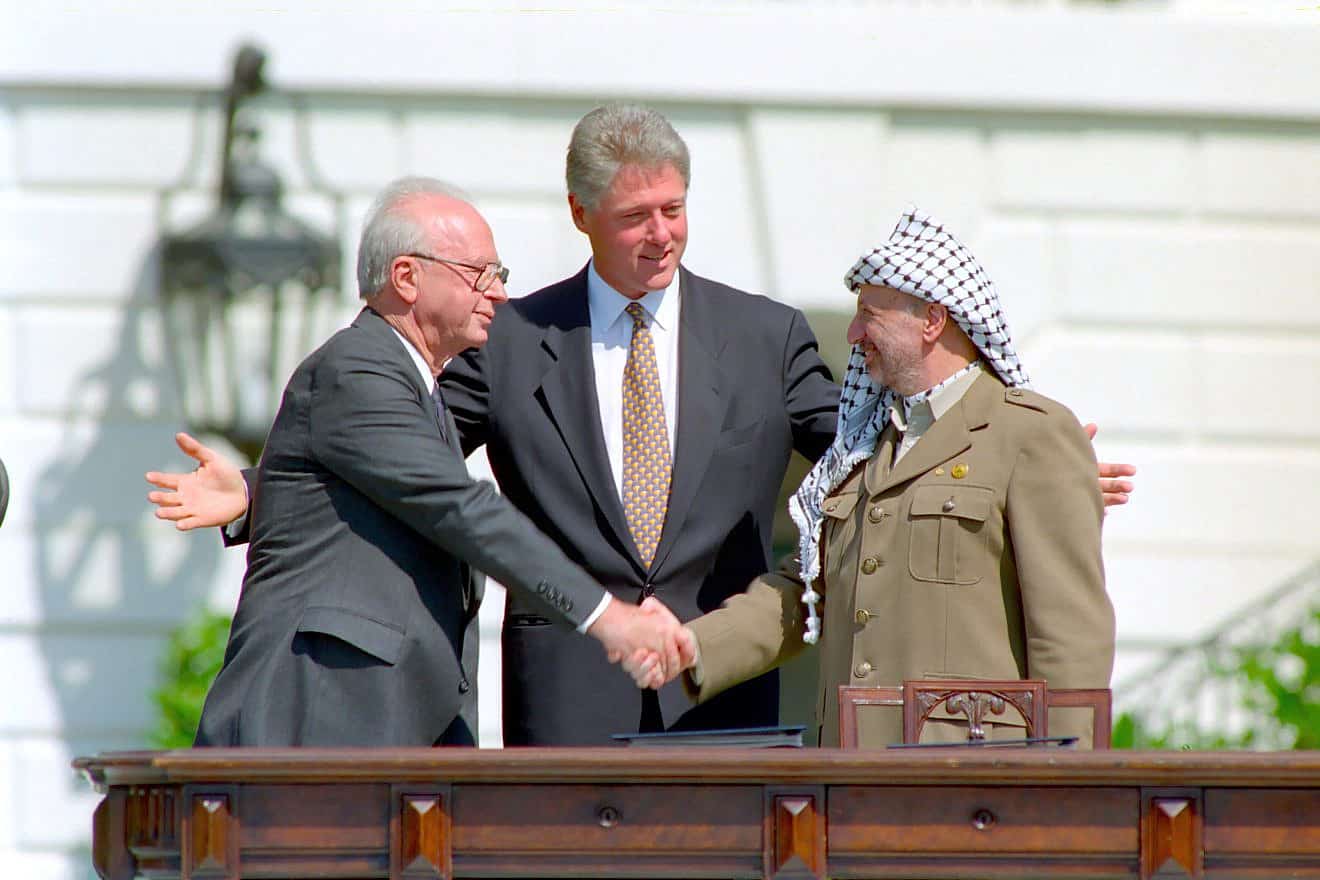 Yitzhak Rabin and Yasser Arafat shaking hands, with Bill Clinton standing between them