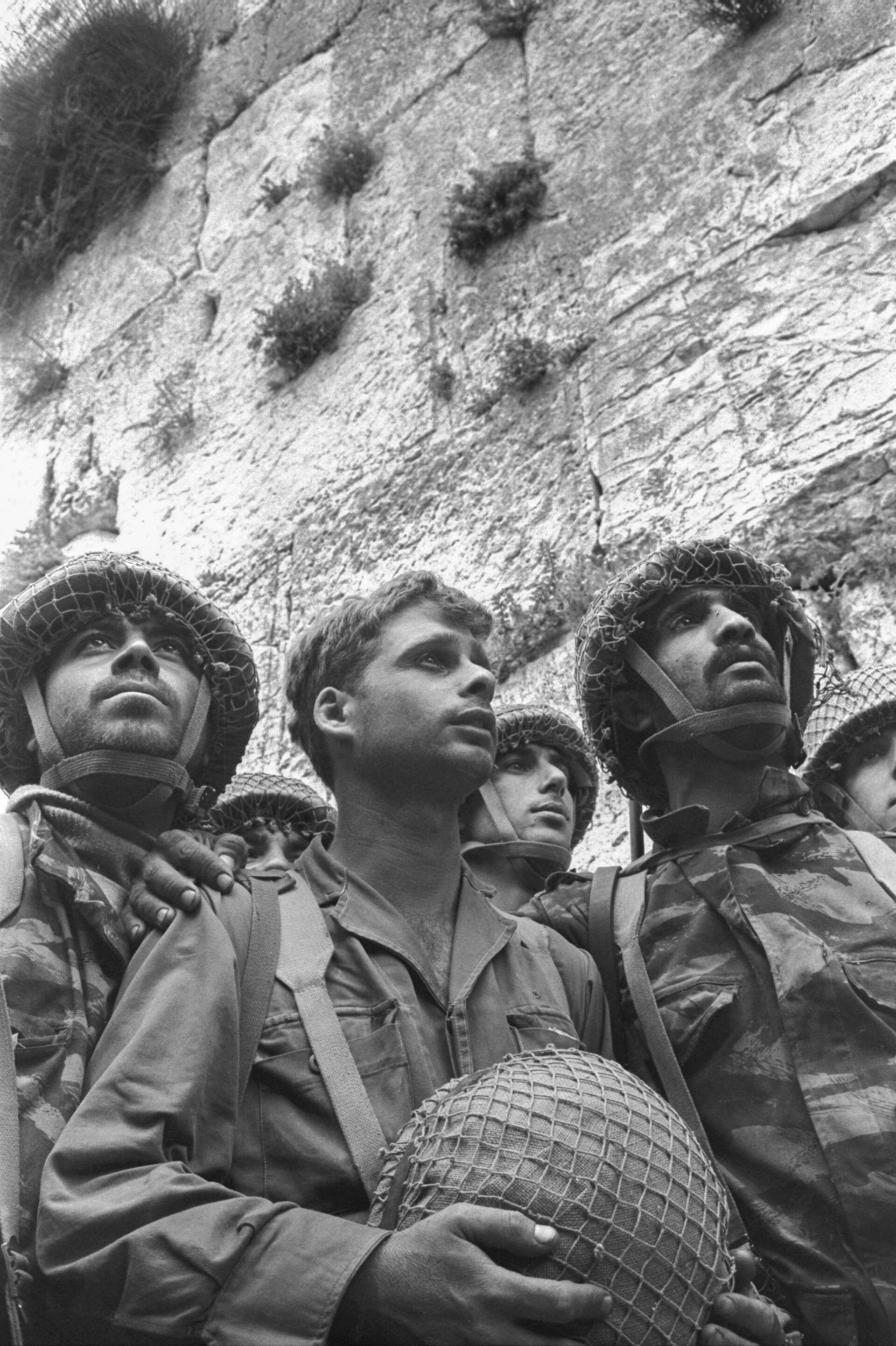 Israeli paratroopers in helmets looking up in front of the stones of the Western Wall