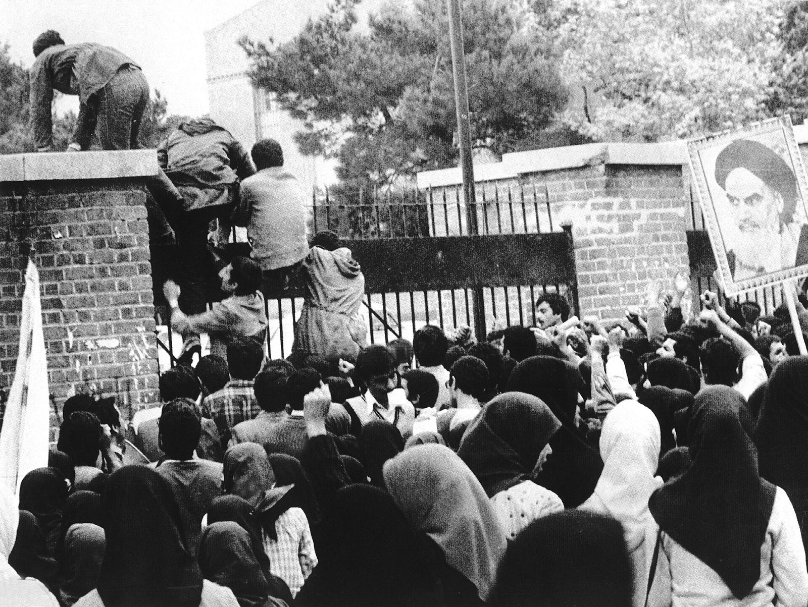 A crowd outside the US embassy in Tehran as people climb over its gate