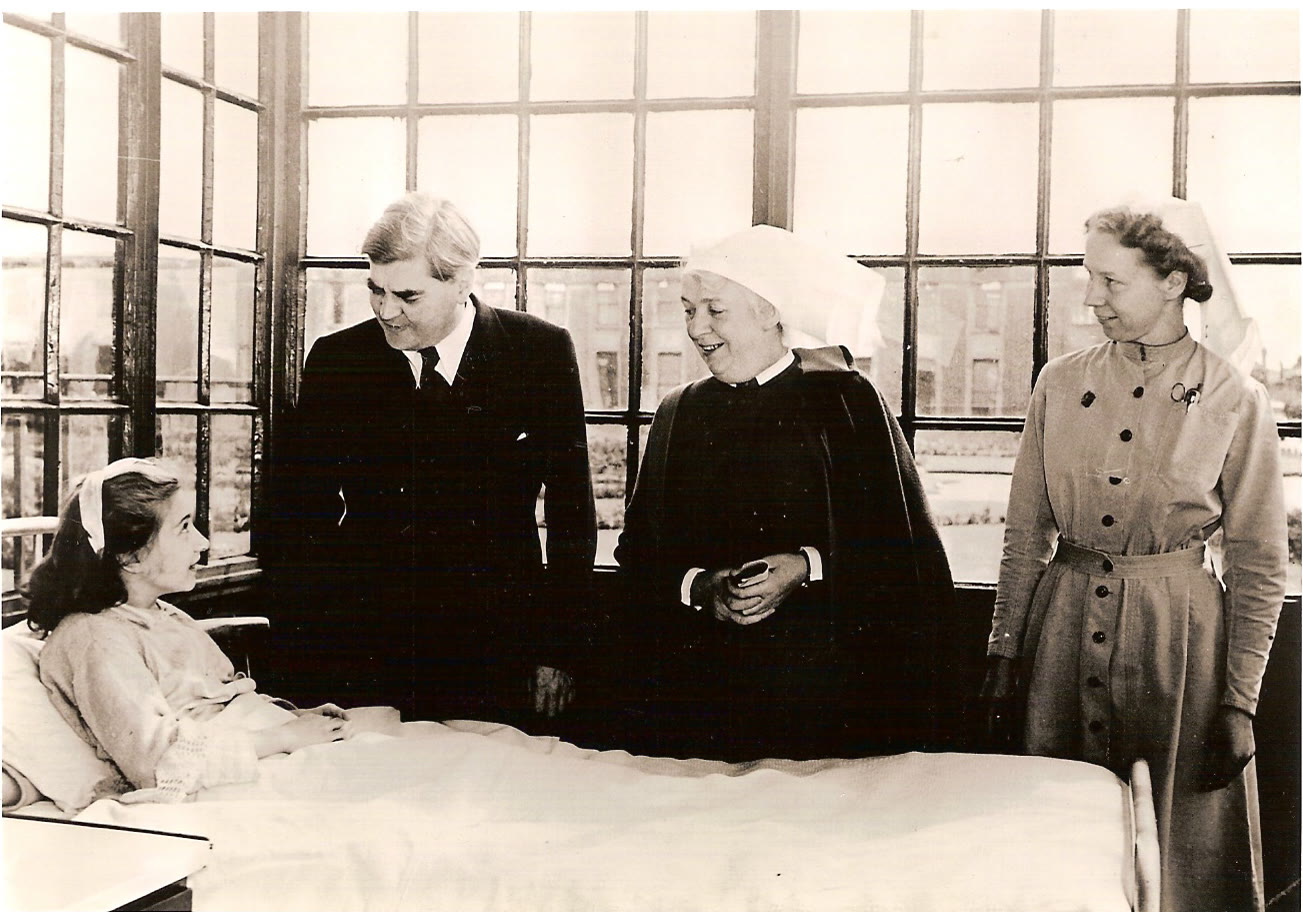 Aneurin Bevan, the Minister of Health, talks to a young patient in bed at Park Hospital near Manchester, with a matron and a nurse, on the NHS's first day, 5 July 1948.